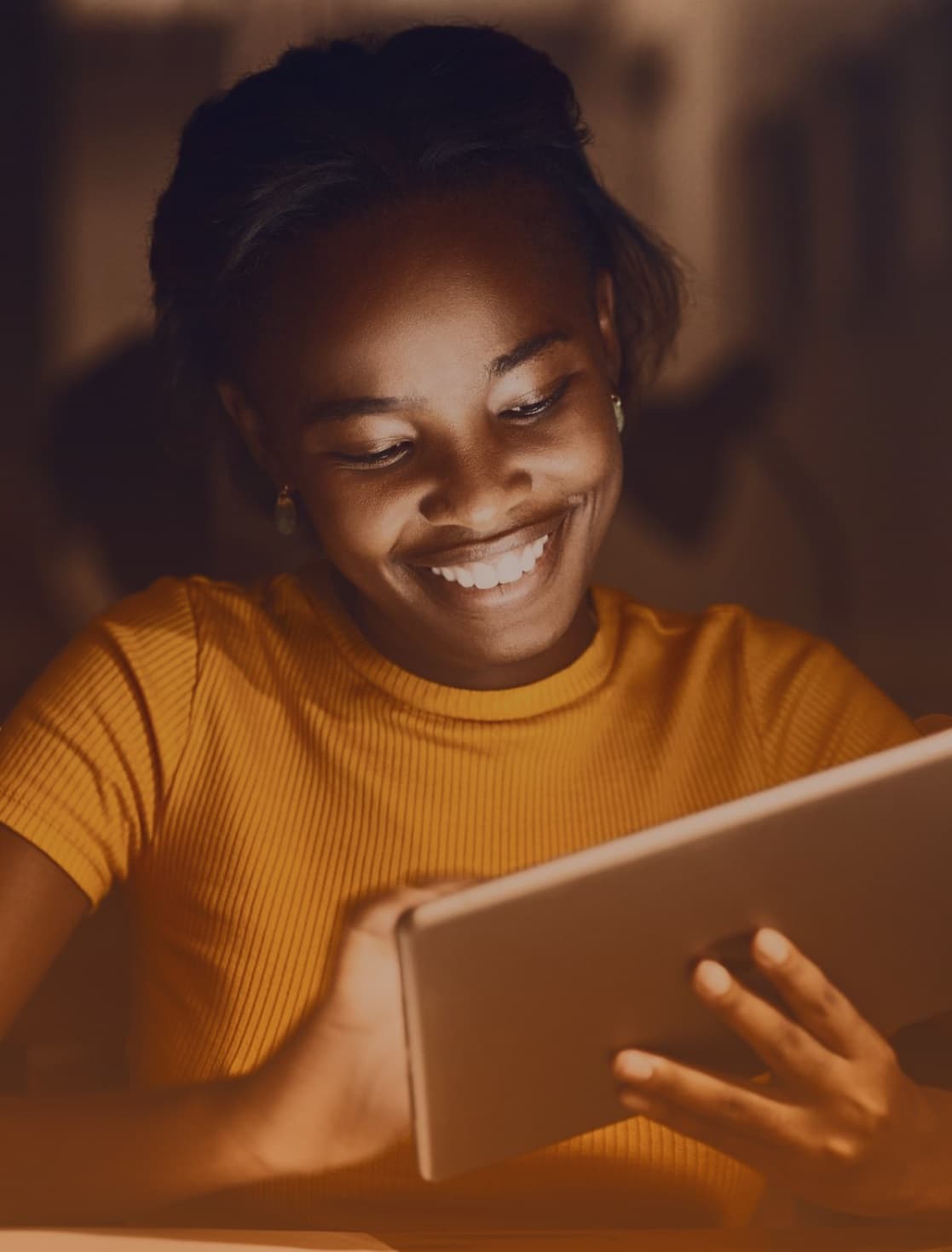 A young woman is absorbed in her reading, captivated by the content on her iPad.