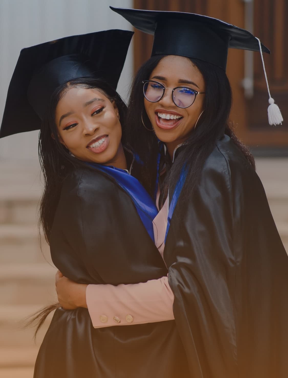 Two women share a heartfelt hug to celebrate their graduation.